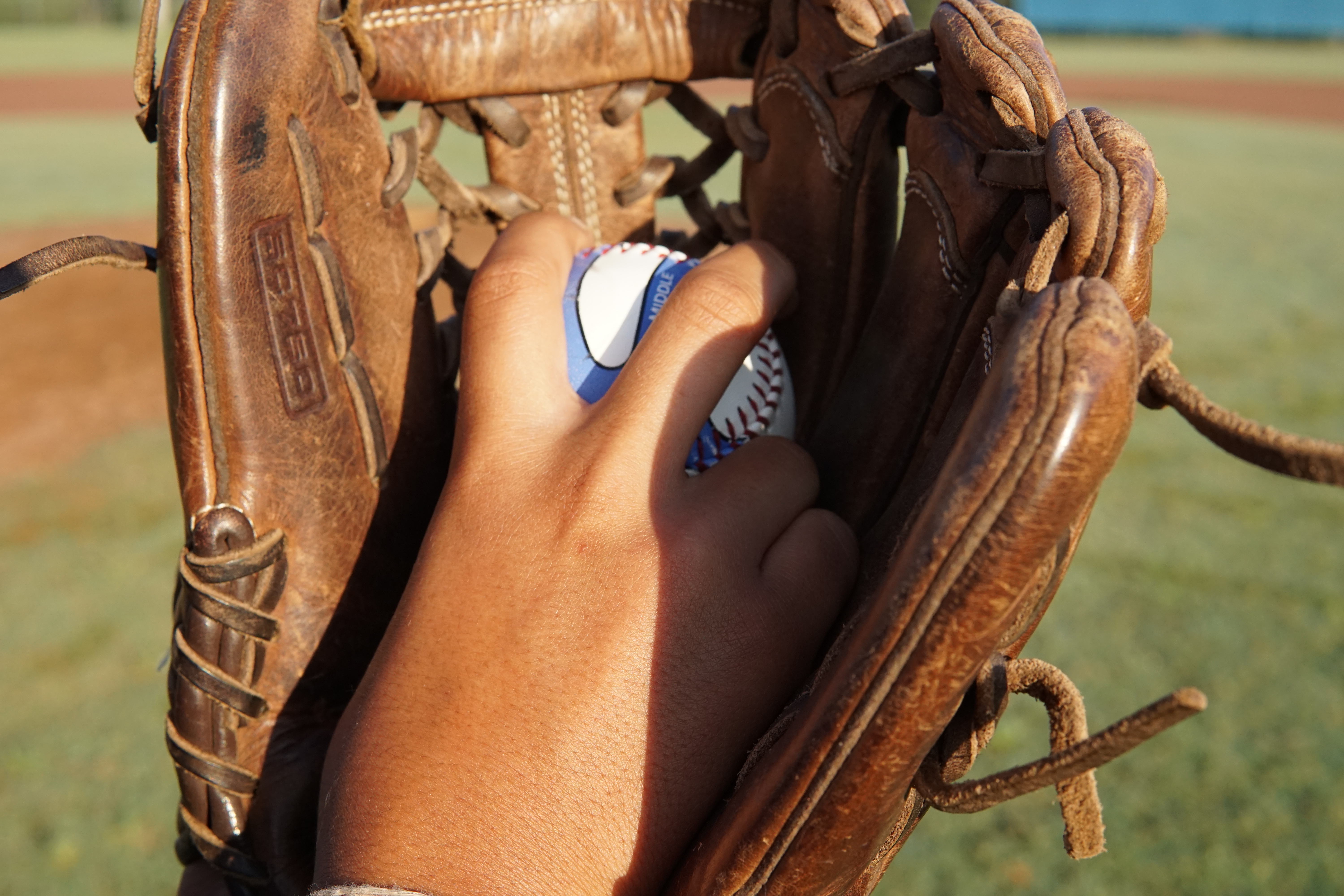 Young pitcher gripping a PitchingPal baseball in a glove